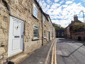 A narrow street lined with stone buildings, featuring a double yellow line road and a manhole cover. - Blueberry Cottage (Malton)