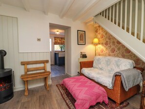 A cozy living room with a fireplace, a bench, a sofa, and a staircase. - Blueberry Cottage (Malton)