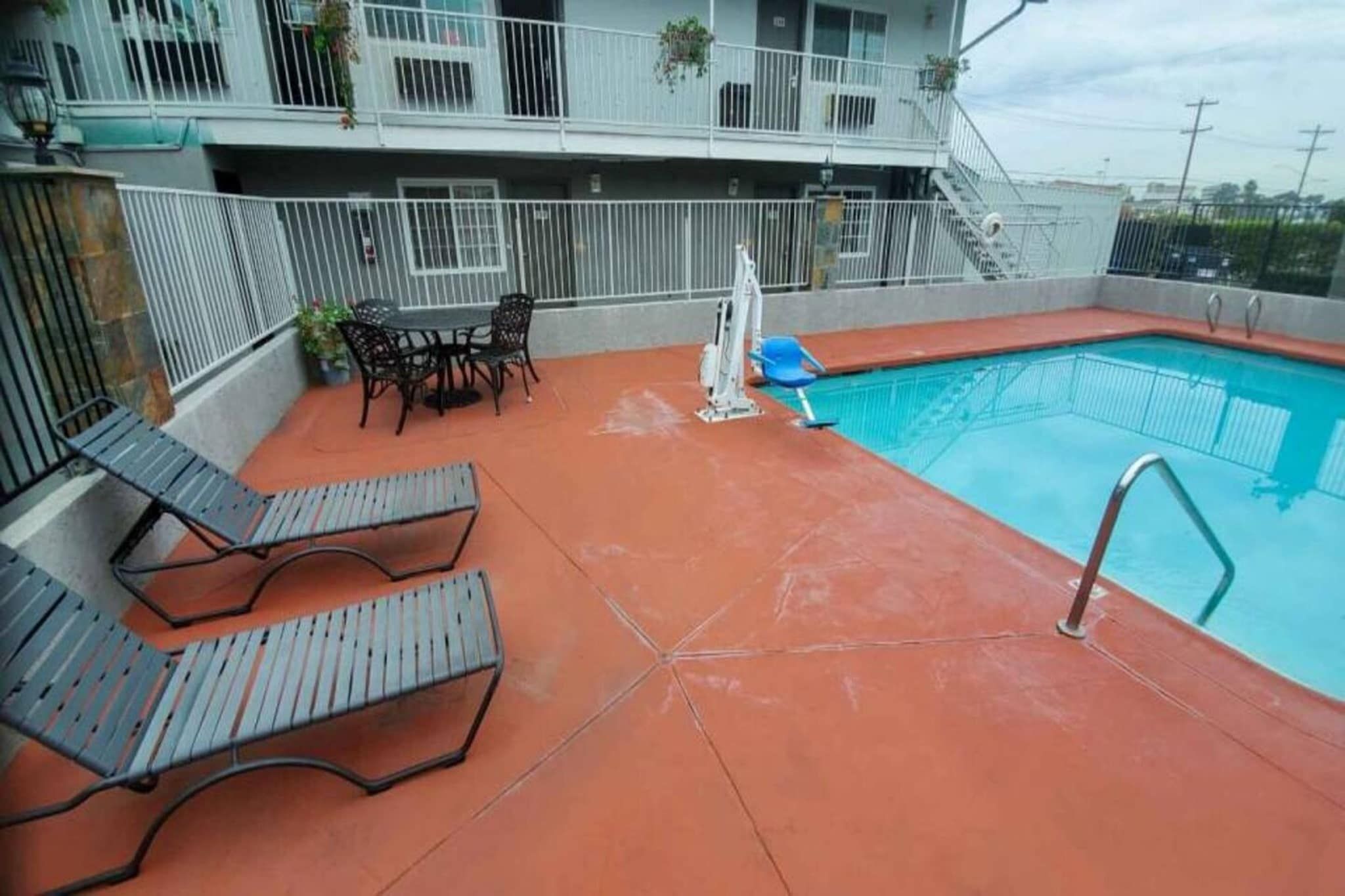 A rooftop pool area with lounge chairs, a table, and a pool.