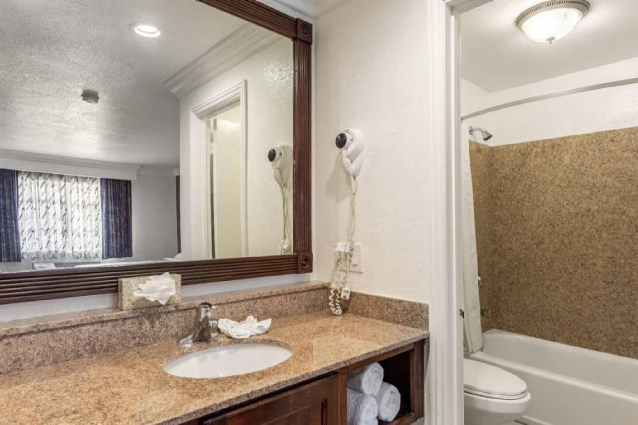 Un baño con lavamanos, espejo, secador de pelo y ducha.