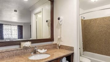 Un baño con lavamanos, espejo, secador de pelo y ducha.