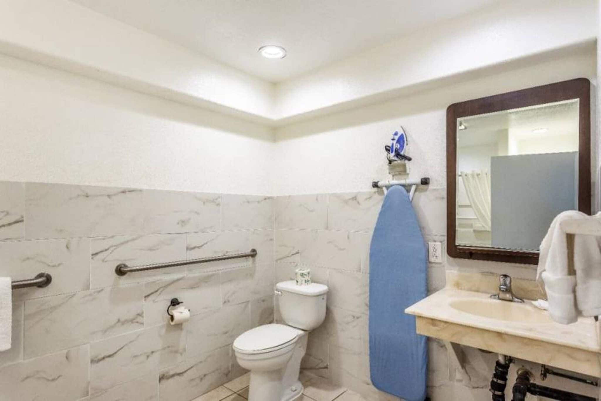 Ein Badezimmer mit Toilette, Waschbecken, Spiegel und Handtuchhalter.