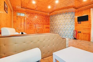 A wooden interior with a sofa, a television mounted on the wall, and a patterned wall. - Townhouse Railway Road Srinagar  (Srinagar)