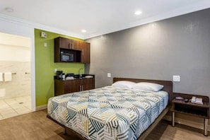 Een hotelkamer met een bed, een klein nachtkastje, een magnetron en een groene wand.