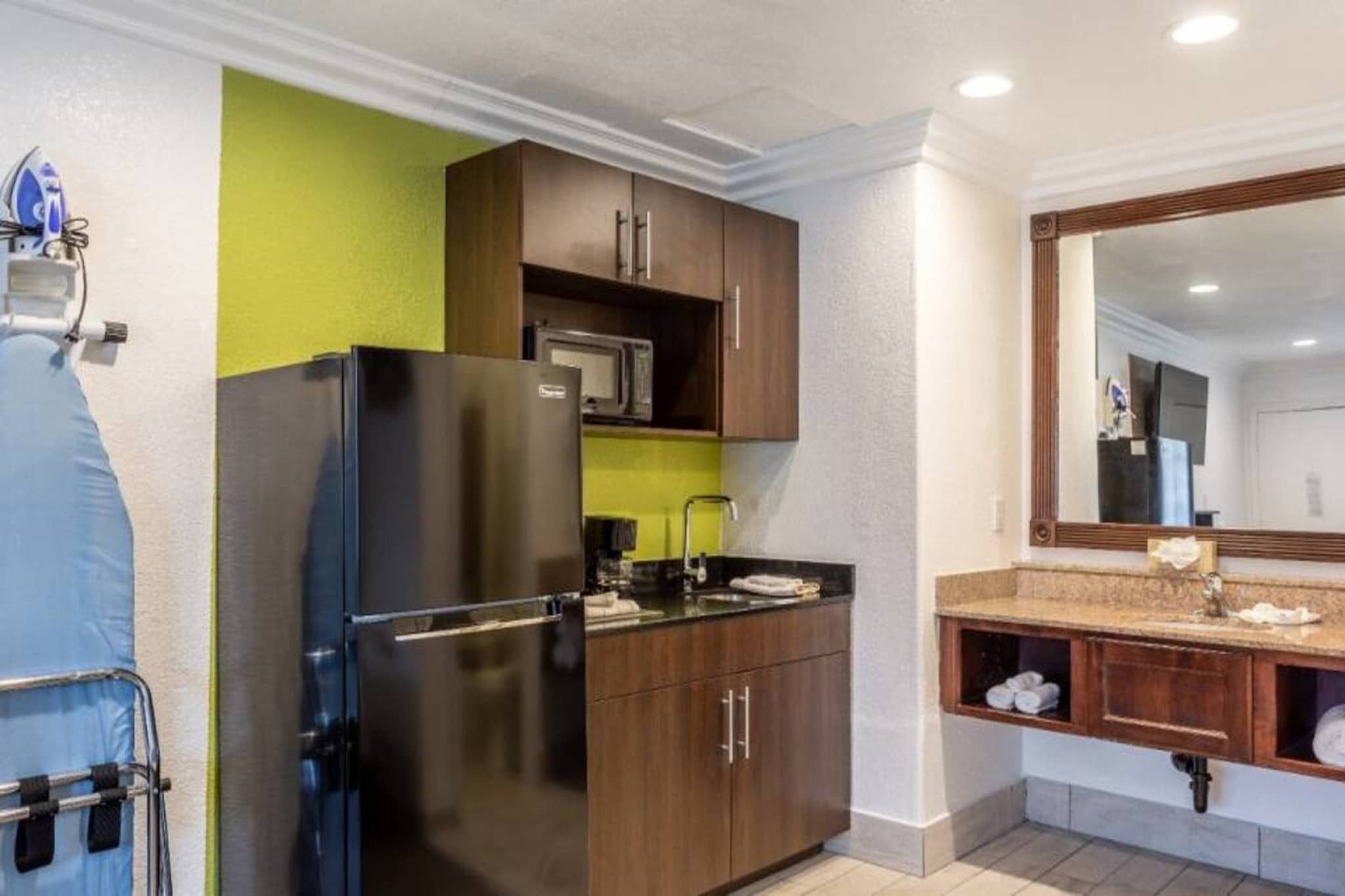 A compact kitchen with a refrigerator, microwave, and wooden cabinets.