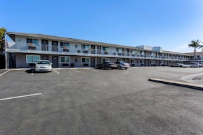 Een motel met diverse parkeerplaatsen en een gebouw met twee verdiepingen en balkons.