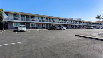 Ein Motel mit mehreren Parkplätzen und einem zweigeschossigen Gebäude mit Balkonen.