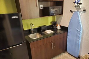 A compact kitchen with a refrigerator, microwave, sink, and coffee maker.