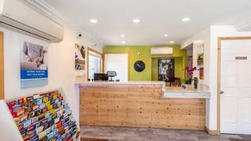 A reception area with a wooden counter, a clock, and a poster on the wall.