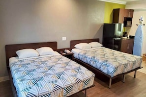 Een hotelkamer met twee bedden, een klein bureau, een koelkast en een magnetron.