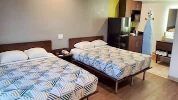A hotel room with two beds, a kitchenette, and a bathroom.