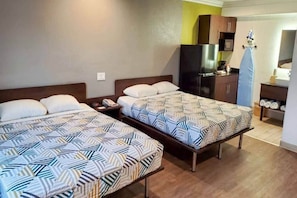 Una habitación de hotel con dos camas, una kitchenette y un baño.