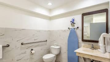 Un baño con inodoro, lavamanos, espejo y toallero.
