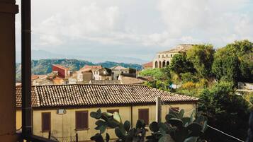 Blick auf eine Stadt mit traditioneller Architektur, ein markantes Gebäude mit Bögen und ein Berg im Hintergrund.