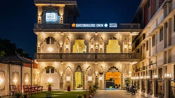 A hotel with a traditional architectural style, featuring ornate balconies and a well-lit entrance.