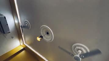 A modern bathroom with a large mirror, a ceiling fan, and recessed lighting.
