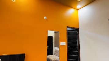 A modern interior with a marble floor, a staircase, a mirror, and a black door.