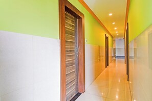 Un pasillo de hotel con una puerta de madera, una pared blanca y una pared verde.