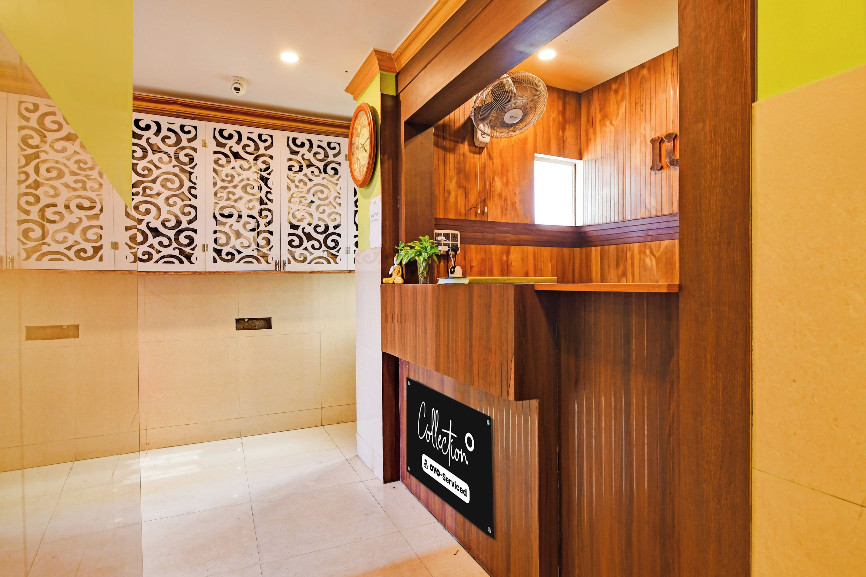 A reception area with a wooden reception desk, a clock, and a sign indicating a self-service option.
