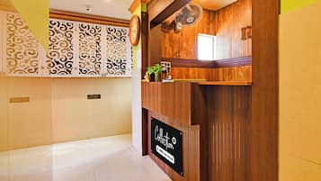 A reception area with a wooden reception desk, a clock, and a sign indicating a self-service option.