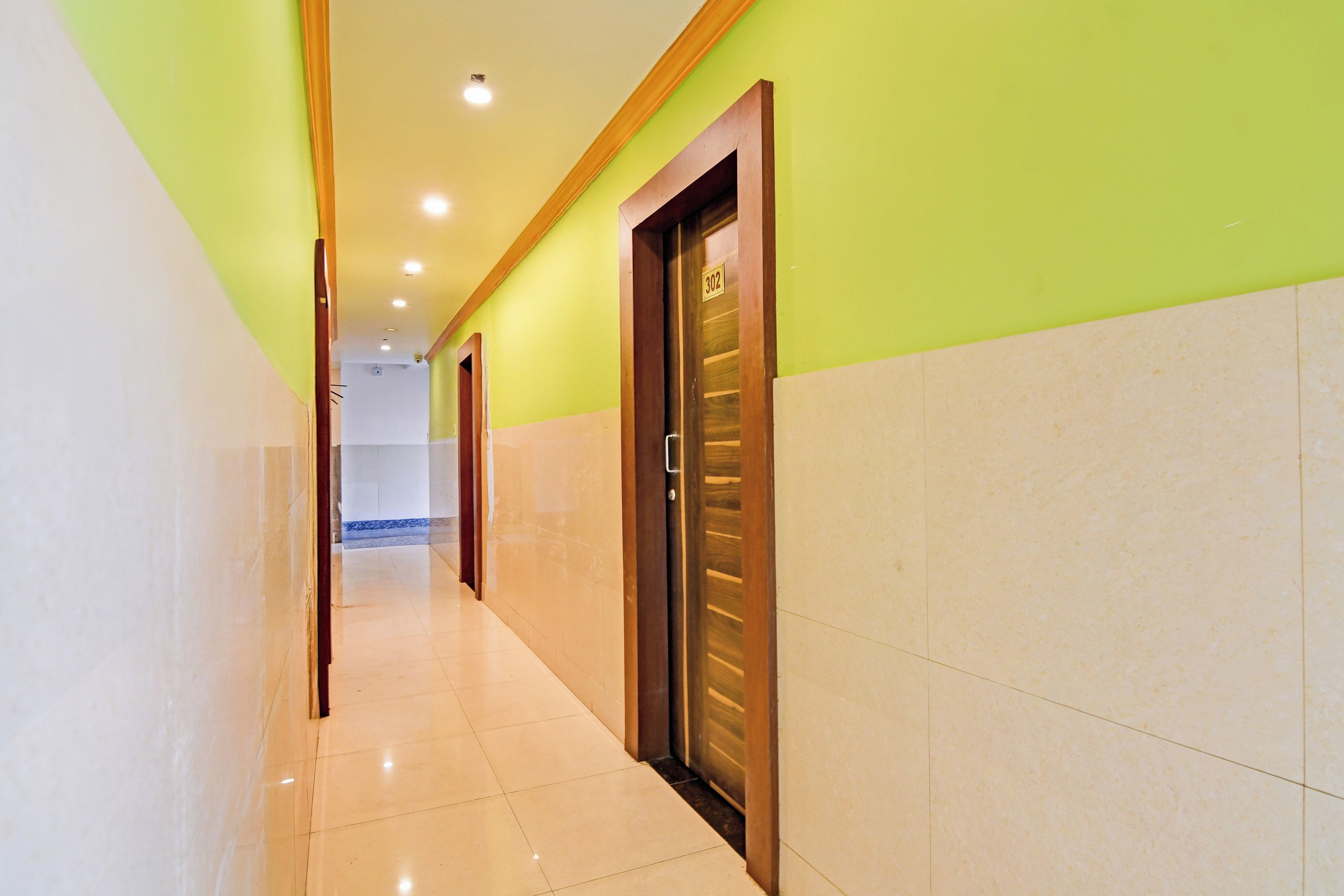 A hotel corridor with a wooden door marked '302', a tiled floor, and a green wall.