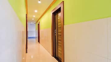 A hotel corridor with a wooden door marked '302', a tiled floor, and a green wall.