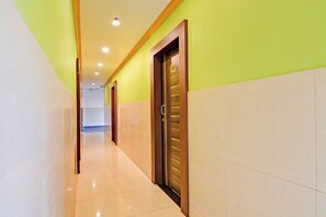 Pasillo de hotel con una puerta de madera identificada como '302', piso de baldosas y pared verde.