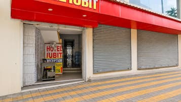 Ein Hotel mit rotem Markisenvorbau, einer Rezeption und geschlossenen Fensterläden.