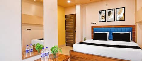 A hotel room with a bed, bedside table, mirror, and wall-mounted artwork.