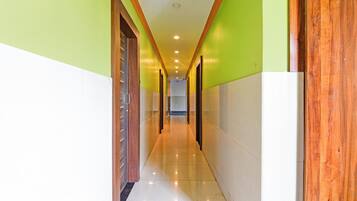 A corridor with a wooden door on the left, a tiled floor, and a green wall on the right.