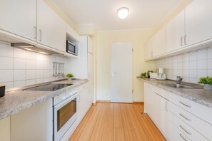 A modern kitchen with white cabinetry, a built-in oven, a microwave, and a stainless steel sink. - Delbrück Villas - House 2 D211 - on the Heringsdorf Promenade (Heringsdorf (Seebad))