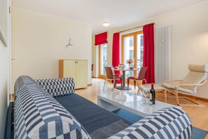 A modern living room with a sofa, a dining table with chairs, and a red curtain. - Delbrück Villas - House 2 D211 - on the Heringsdorf Promenade (Heringsdorf (Seebad))