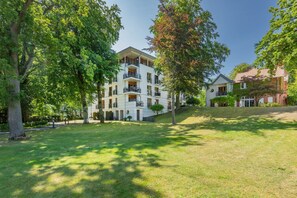 A multi-story building with balconies, surrounded by lush greenery and trees. - Delbrück Villas - House 2 D211 - on the Heringsdorf Promenade (Heringsdorf (Seebad))
