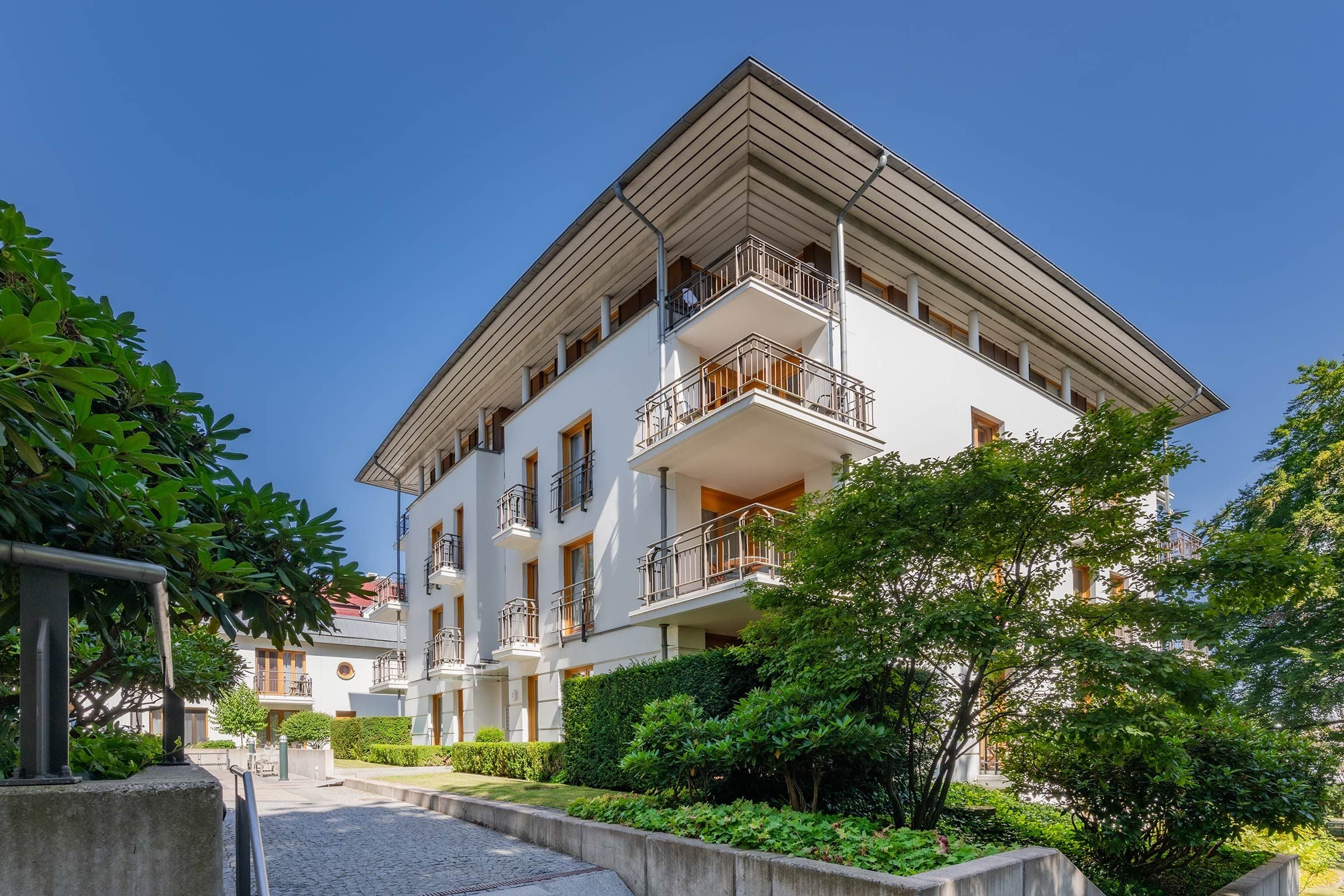 A multi-story building with balconies, a courtyard, and surrounding greenery.