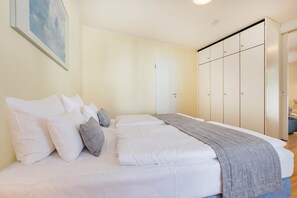 A bedroom with a bed, pillows, a blanket, a wardrobe, and a door. - Delbrück Villas - House 2 D211 - on the Heringsdorf Promenade (Heringsdorf (Seebad))