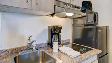A kitchenette with a stainless steel sink, a coffee maker, a microwave, and a refrigerator.