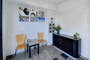 Un espace d’accueil comprenant un bureau, deux chaises, une petite table et une plante en pot.