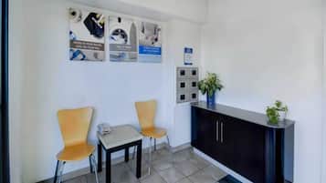 Un espace d’accueil comprenant un bureau, deux chaises, une petite table et une plante en pot.