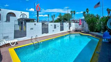 A swimming pool with a blue and yellow border, a white fence, and a number '6' sign.