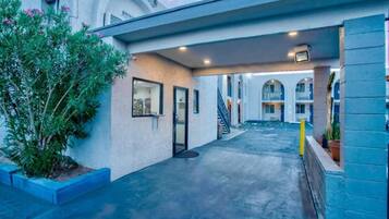 A hotel corridor with a covered walkway, a staircase, and a pool area.