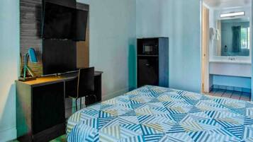 A hotel room with a bed, a desk, a television, a wardrobe, and a bathroom.