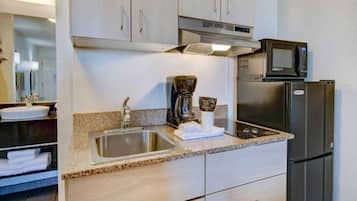 A kitchenette with a stainless steel sink, a coffee maker, a microwave, and a refrigerator.