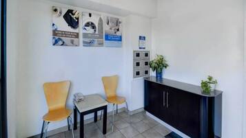 A reception area with a desk, two chairs, a small table, and a potted plant.