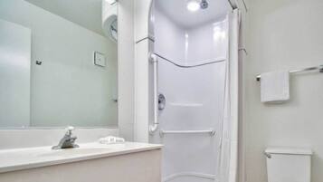 Ein Badezimmer mit Duschkabine, Waschbecken, Toilette und Spiegel.