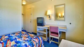 Une chambre d’hôtel comprenant un lit, un bureau avec une chaise, une télévision et un miroir.