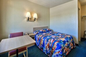 Habitació d'hotel amb un llit, una taula de treball, una cadira i dues làmpades penjades a la paret.