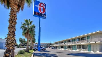 Un motel con un letrero azul, un estacionamiento y un edificio con varias ventanas.