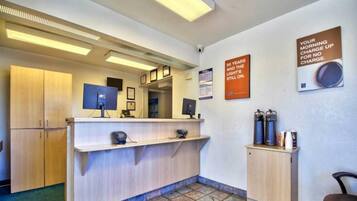 Un espace d’accueil avec un comptoir, une machine à café et deux affiches au mur.