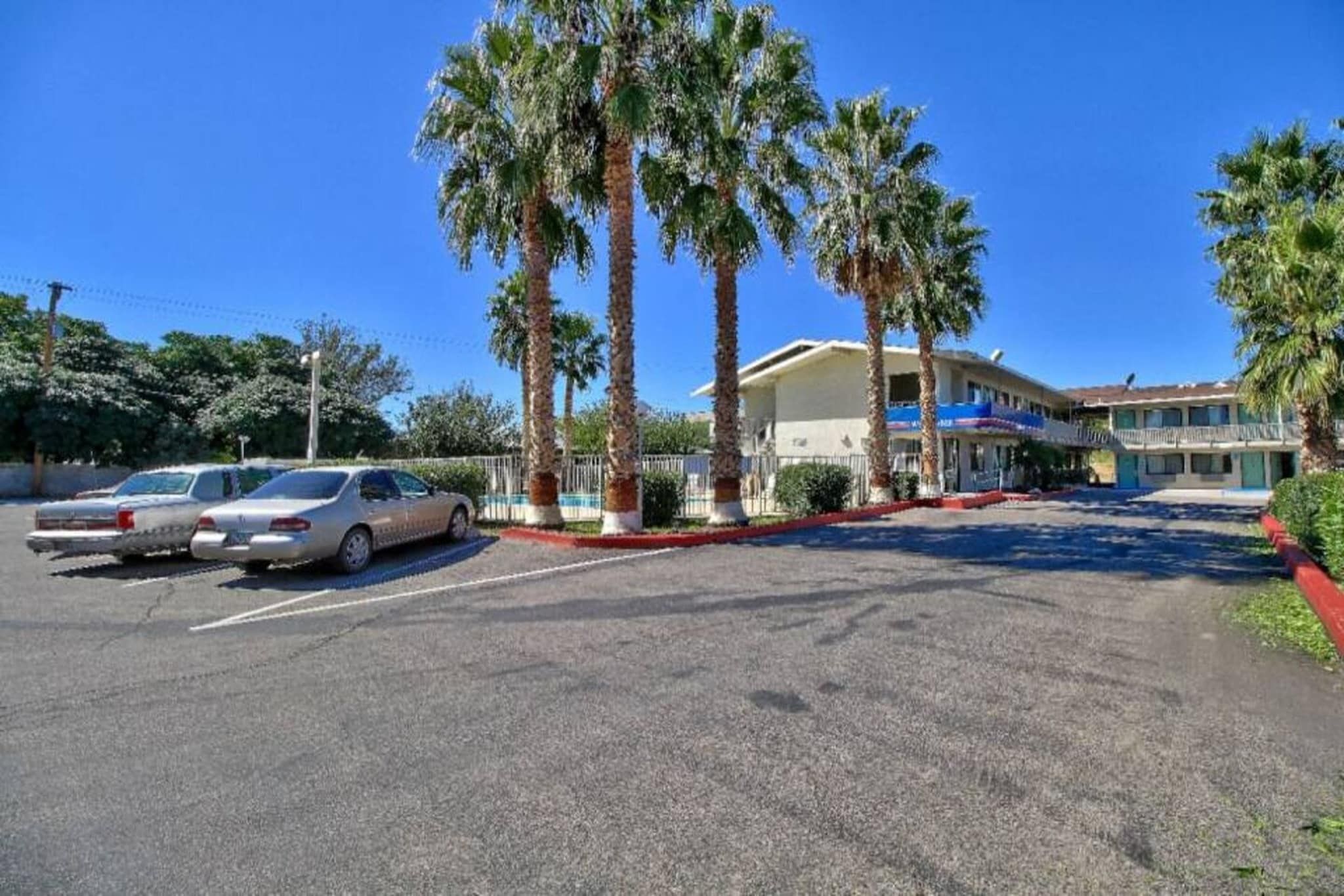 A parking lot with a building that has a blue awning and a red curb.