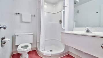 A bathroom with a toilet, a shower, and a sink.